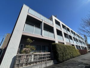 白いタイル張りの4階建て介護施設の建物外観。晴天下での正面からの撮影。